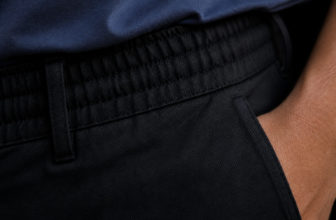Gros plan sur la taille élastique d'un pantalon noir porté avec un t-shirt bleu.